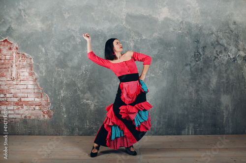 Young adult spanish woman dancing flamenco on gray vintage background