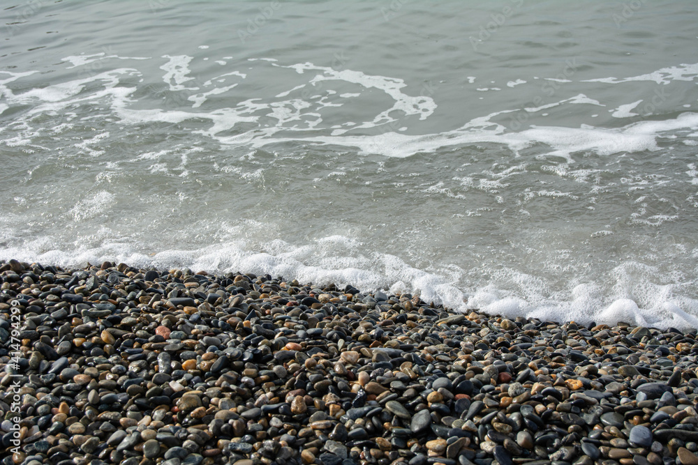 The sea wave covers the pebble beach The sea wave covers the pebble beach