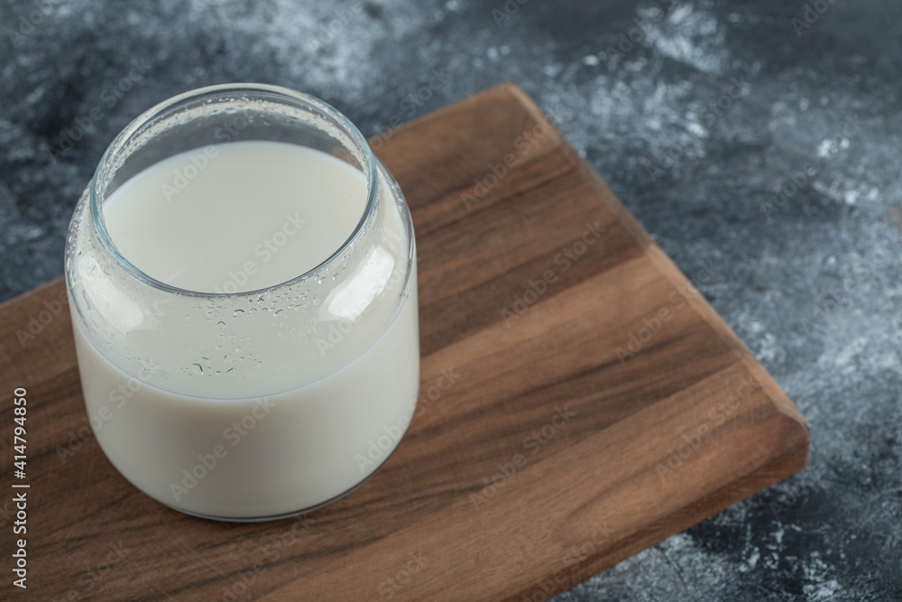 Glass of fresh milk on wooden board