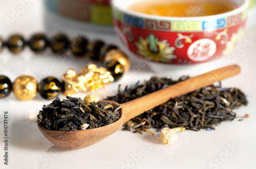 Green tea in a spoon with blurred tea cub on the background 