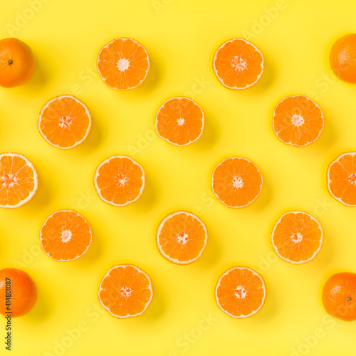 Fruit pattern of fresh mandarin slices on yellow background. Flat lay, top view. Pop art design, creative summer concept. Half of citrus in minimal style. Tangerine.