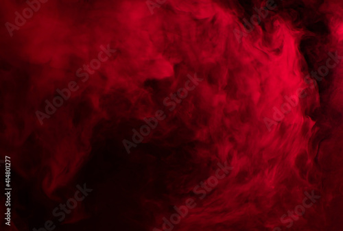 Abstract background of chaotically mixing puffs of red smoke on a dark background