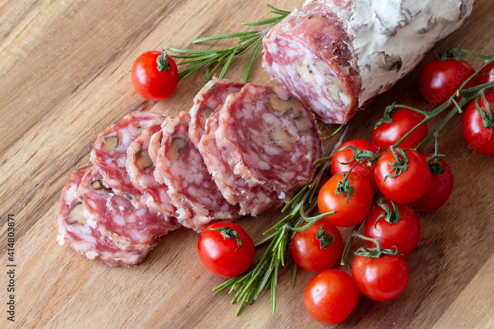 Sliced Air-dried salami with rosemary and cherry tomatoes - wood background Sliced Air-dried salami with rosemary and cherry tomatoes - wood background