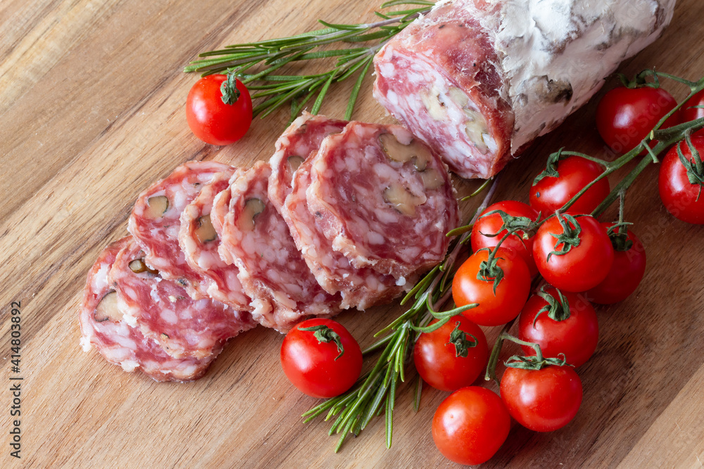 Sliced Air-dried salami with rosemary and cherry tomatoes - wood background Sliced Air-dried salami with rosemary and cherry tomatoes - wood background