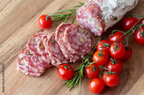 Sliced Air-dried salami with rosemary and cherry tomatoes - wood background