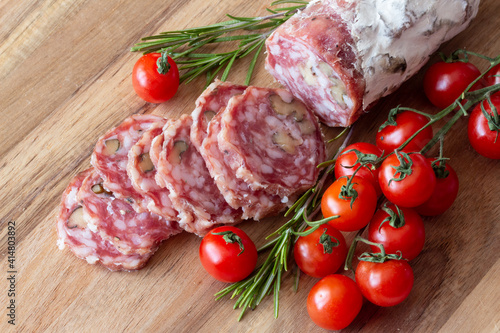Sliced Air-dried salami with rosemary and cherry tomatoes - wood background