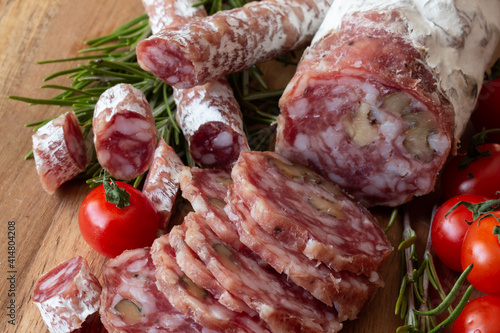 Sliced Air-dried salami with rosemary and cherry tomatoes - wood background