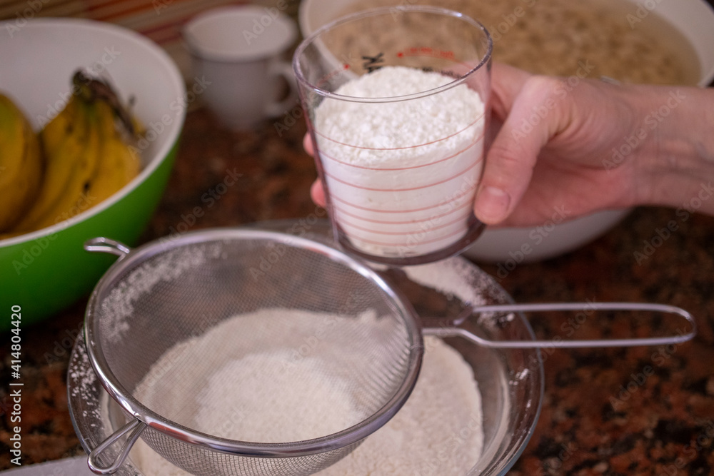 Woman's hand measuring flour with measuring glass, working in the kitchen.
Woman's hand measuring flour with measuring glass, working in the kitchen.