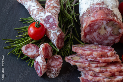 Sliced Air-dried salami with rosemary and cherry tomatoes - grey stone background