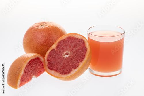 Juicy grapefruit with glass of freshly squeezed juice on white