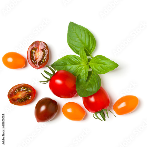 various colorful tomatoes and basil leaves isolated on white background. Top view, flat lay. Creative layout..