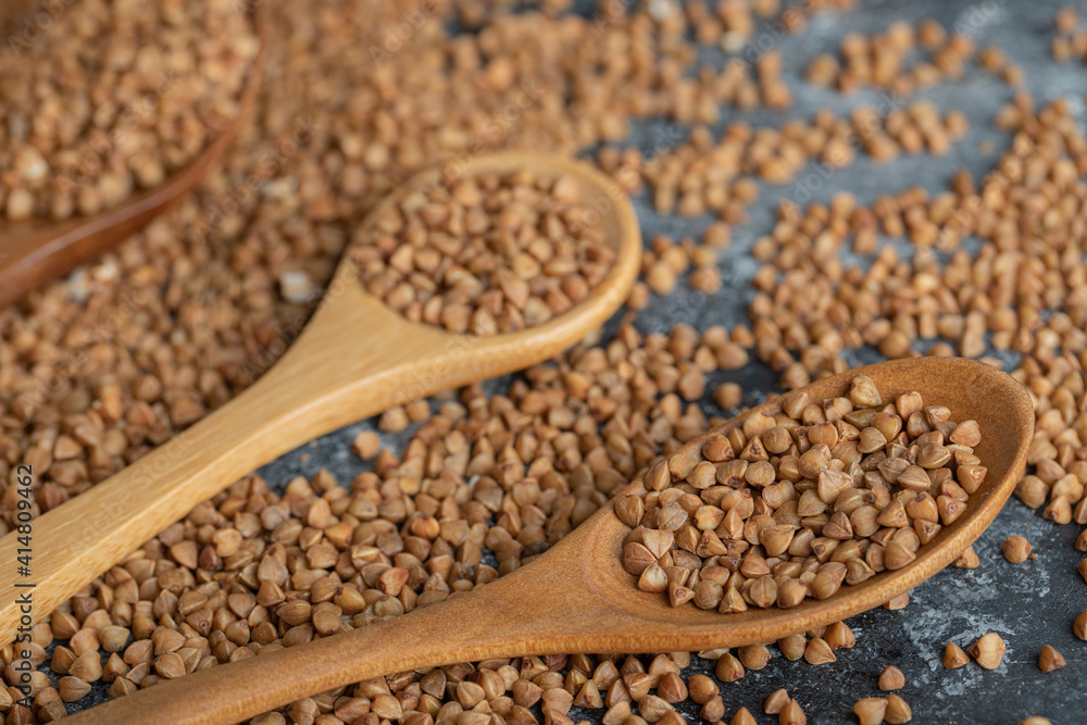 Two wooden spoons full of raw buckwheat Two wooden spoons full of raw buckwheat