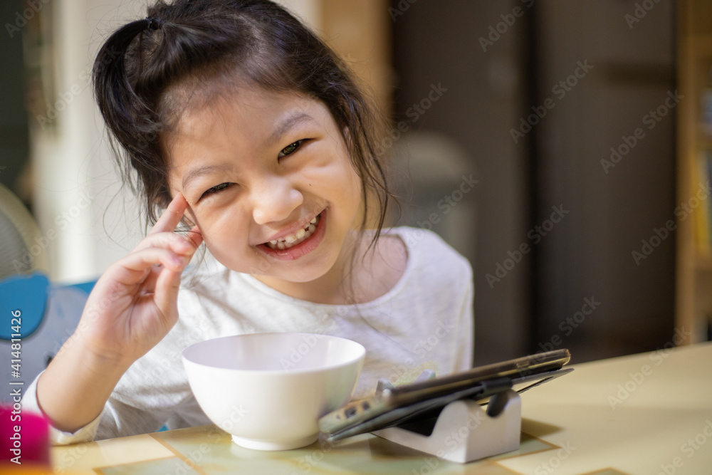 Happy asian girl eating with smartphone at home. New normal. Social distancing. stay home Happy asian girl eating with smartphone at home. New normal. Social distancing. stay home