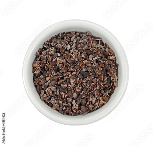 Cocoa nibs in a bowl, a pieces of broken cocoa beans isolated, top view