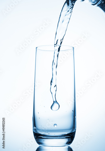 water pouring into glass over blue background.