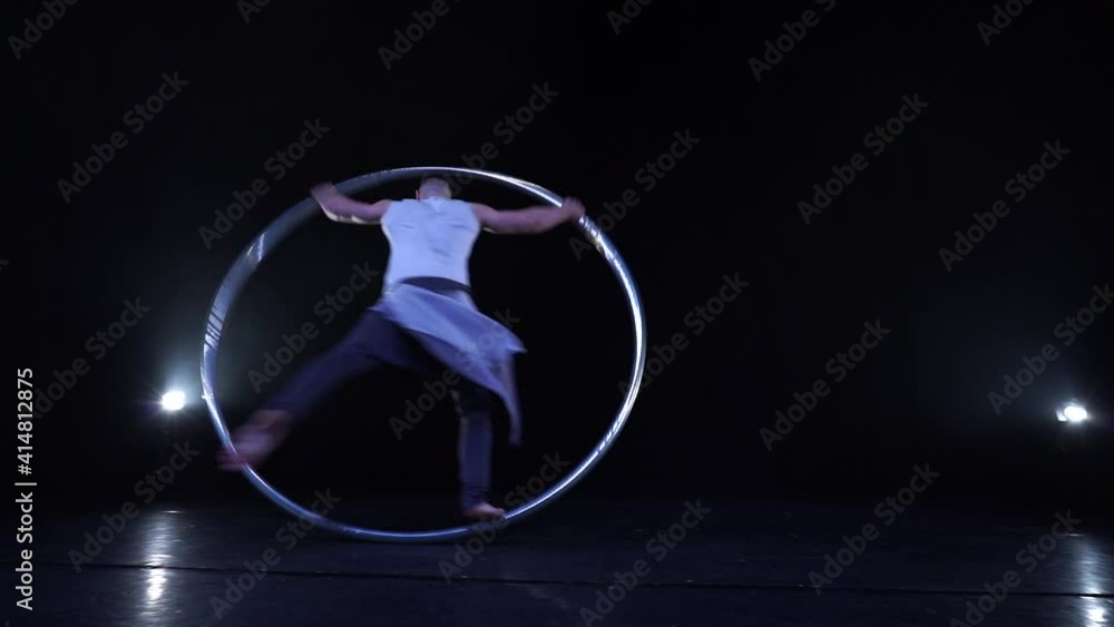Muscular Circus artist spinning on a Cyr wheel in slow motion. Concept of movement, motion and balance Muscular Circus artist spinning on a Cyr wheel in slow motion. Concept of movement, motion and balance