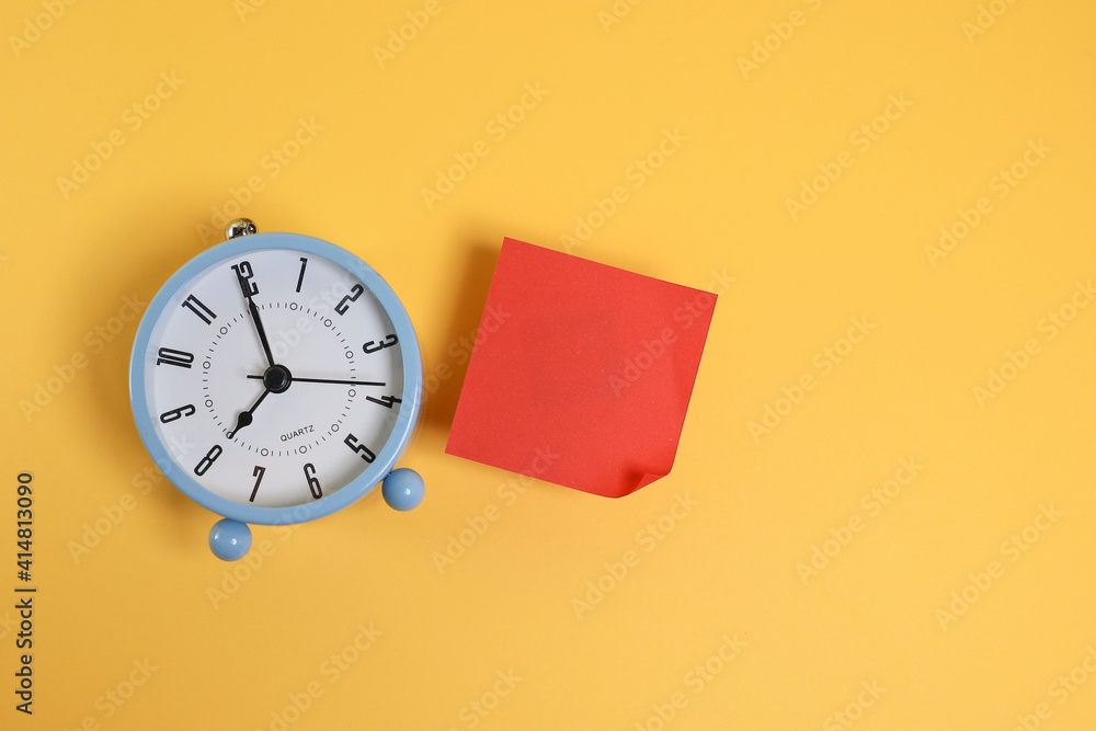Red paper and alarm clock isolated on the yellow background Red paper and alarm clock isolated on the yellow background