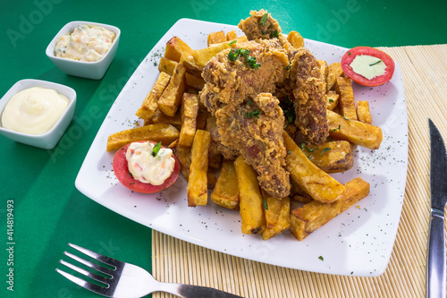 Plato de comida hecho de chicharrón de pollo, frito, broaster con papas fritas en plato blanco para restaurante en fondo verde photo