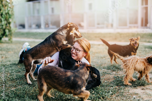 Young adult woman playing with adorable dogs in animal shelter. photo
