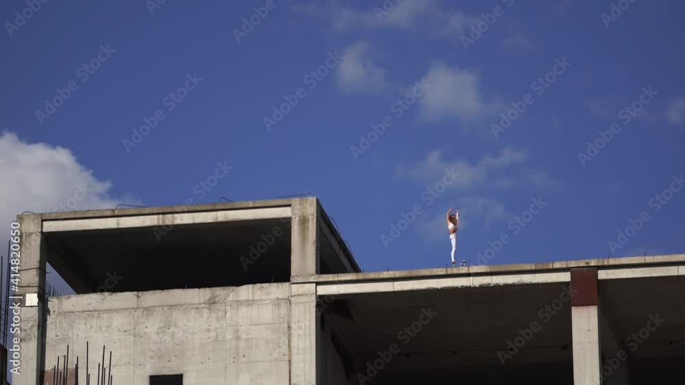 Flexible woman standing on the edge of building under construction. Freedom, courage and willpower concept Flexible woman standing on the edge of building under construction. Freedom, courage and willpower concept