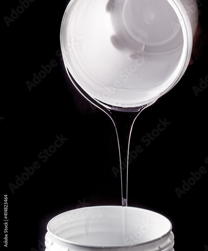 Transparent liquid silicone being poured out of a jar photo