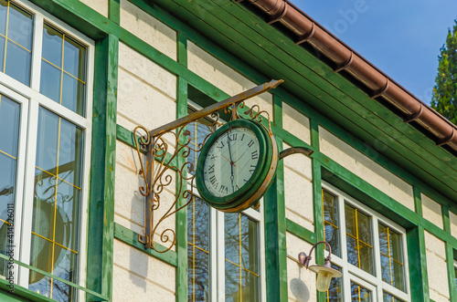 An old large round clock on the wall of a wooden house.