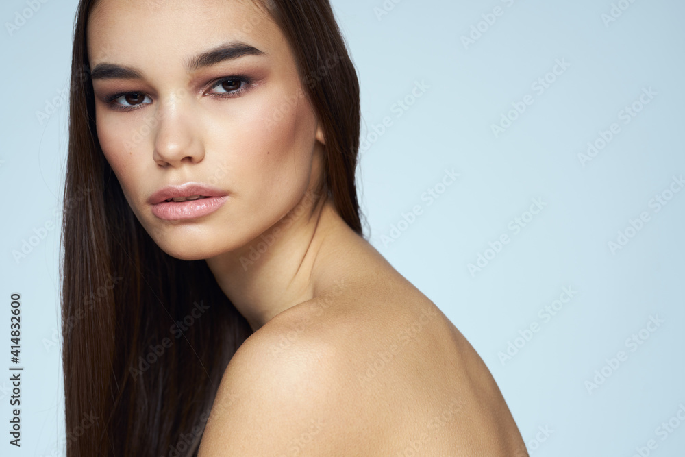 Pretty brunette with bared shoulders long hair body care blue background Pretty brunette with bared shoulders long hair body care blue background