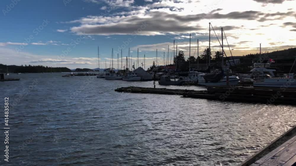 Multiple luxury sail yachts moored at wooden scaffoldings in Ganges Marina on Salt Spring Island on a partly cloudy day. Slowly tilt shot Multiple luxury sail yachts moored at wooden scaffoldings in Ganges Marina on Salt Spring Island on a partly cloudy day. Slowly tilt shot