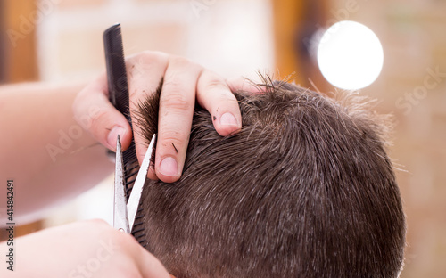 Male hairdresser, grooming men. Haircut styler and trimmer. The master cuts a man, shaves his temples and neck. The client at the hairdresser looks in the mirror. barbershop