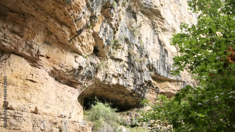 Natural Cave entrance in the rock near the forest Natural Cave entrance in the rock near the forest