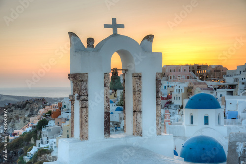 Sunset view of churches and blue cupolas of Oia town at Santorini, Greece photo