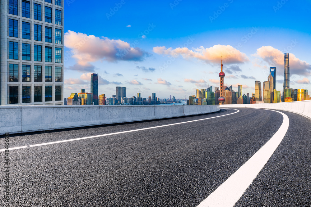 Empty asphalt road and Shanghai skyline with buildings at sunset.