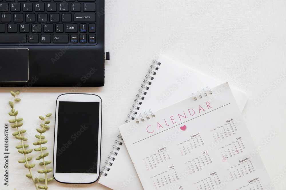 notebook planner calendar ,computer and mobile phone for business work at office desk arrangement flat lay style on background white notebook planner calendar ,computer and mobile phone for business work at office desk arrangement flat lay style on background white