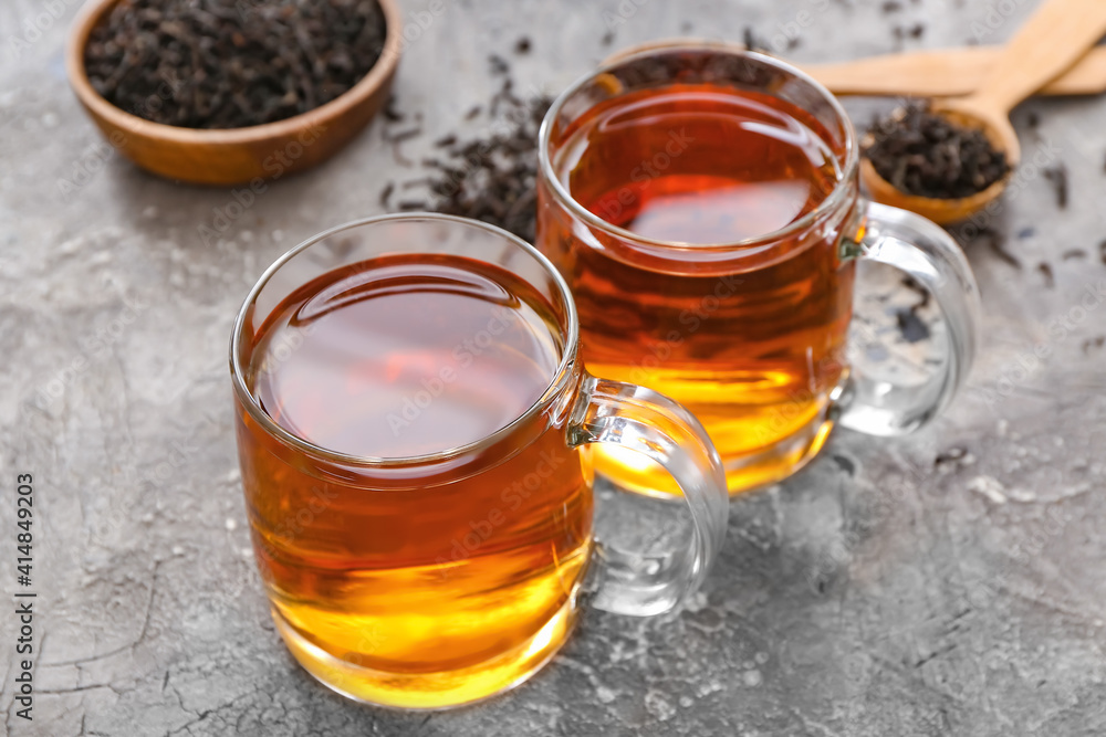 Fototapeta premium Cups of tea and dry leaves on dark background, closeup