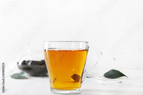 Cup of tea and dry leaves on light background