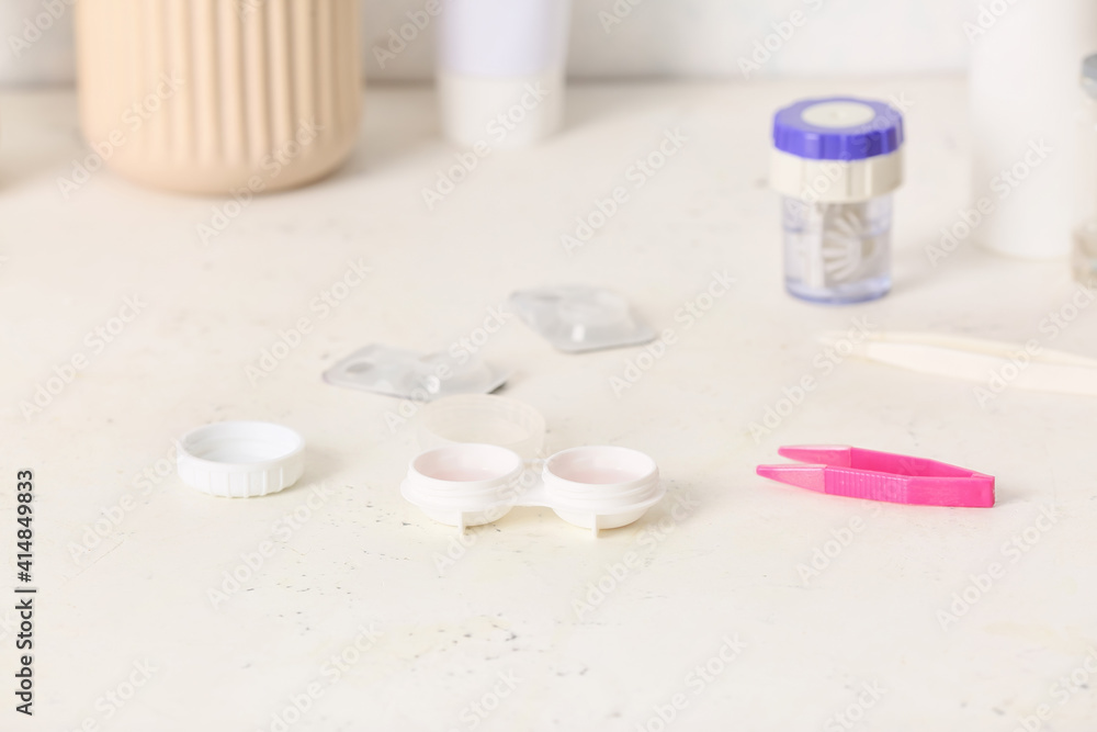 Tweezers and container with contact lenses on light background Tweezers and container with contact lenses on light background