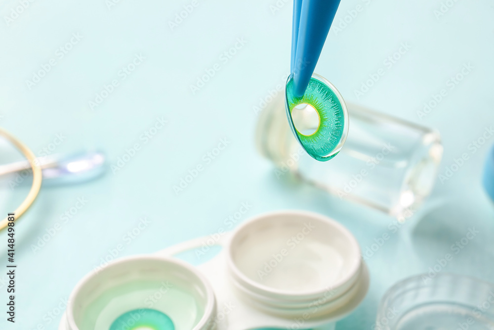 Tweezers with contact lenses on color background Tweezers with contact lenses on color background