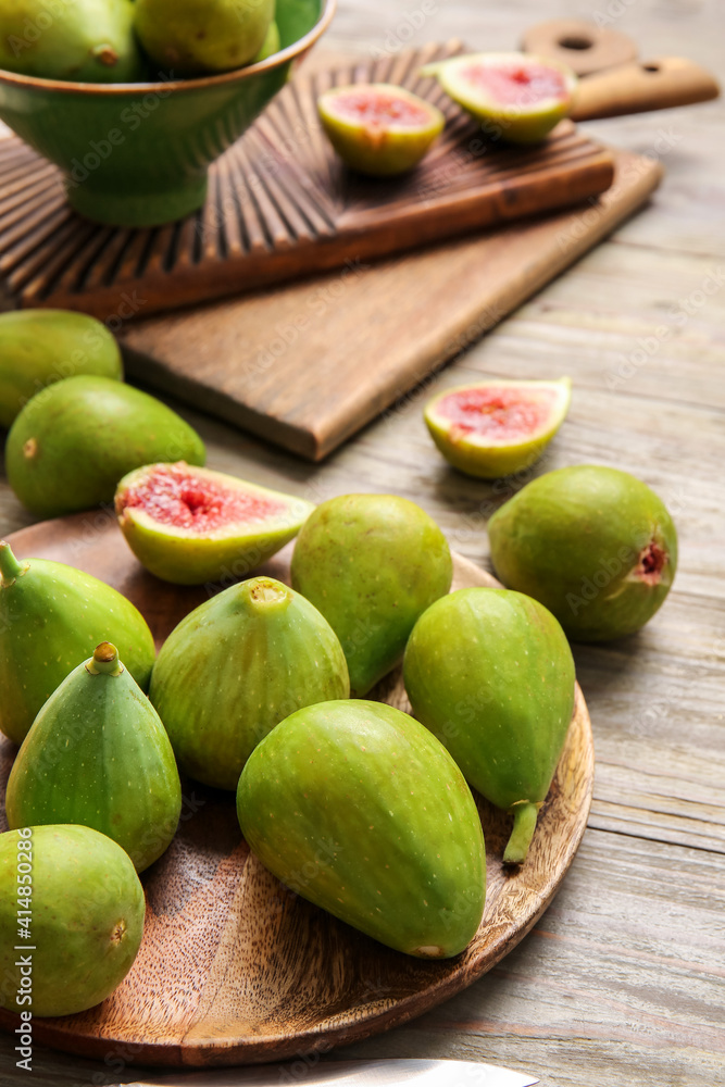 Plate with fresh green figs on wooden background, closeup