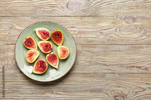 Plate with fresh green figs on wooden background