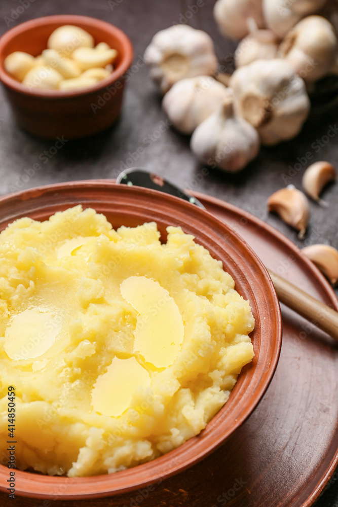Plate with tasty mashed potatoes and garlic on dark background Plate with tasty mashed potatoes and garlic on dark background