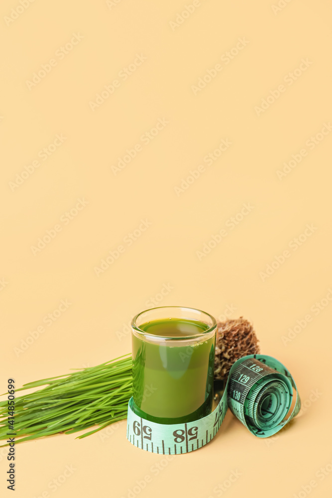Fototapeta premium Glass with fresh wheatgrass juice and measuring tape on color background