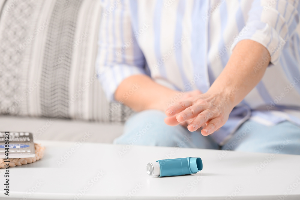 Mature woman taking inhaler from table
