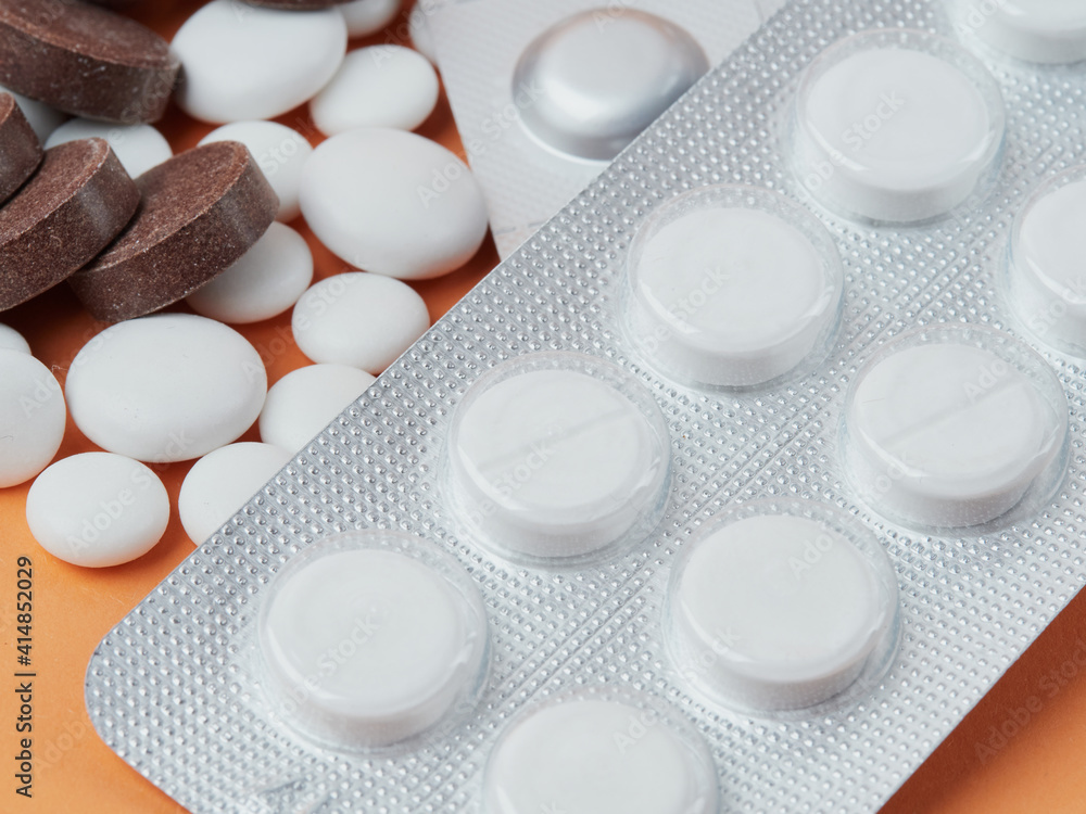 various white tablets on an orange background various white tablets on an orange background