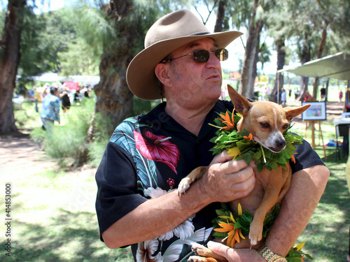 Man holding Small dog wearing a Lei at Lei day Celebrations in Waikiki, Ohau, Hawaii