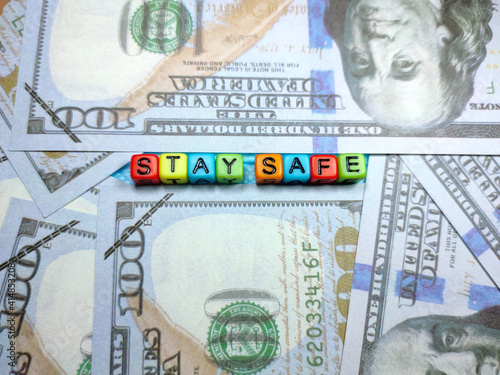 Selective focus of text STAY SAFE from colorful cube on face mask with banknote.Shot were noise and grain.