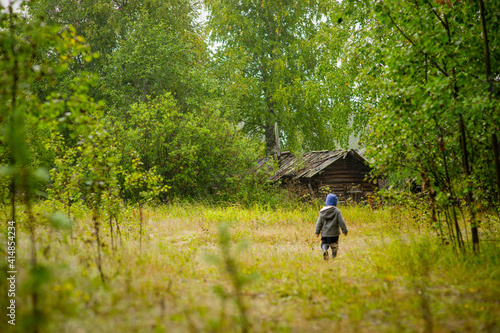 a little boy walks through the woods to a wooden house, selective focus