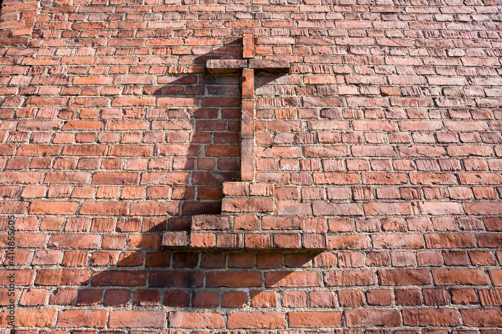 Christian cross on red brick wall