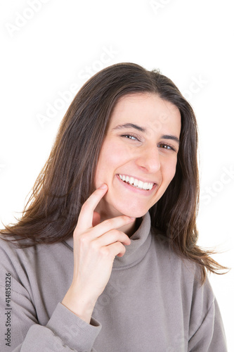 beautiful young radiant woman with hand under chin happy and smiling with long brown hair