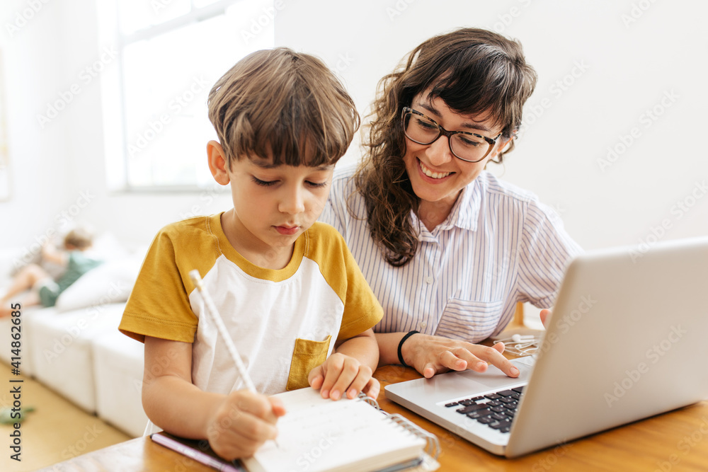 Boy doing homework with mother working Boy doing homework with mother working