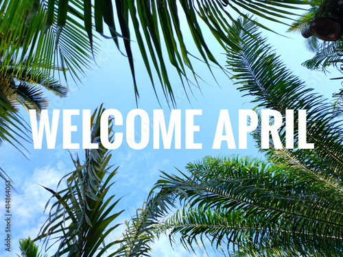 Selective focus.Word WELCOME APRIL with green tree and blue sky background.Shot were noise and film grain. © Mohd Azrin